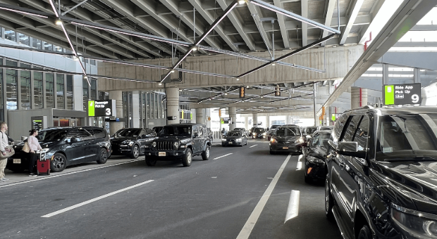 Newark Airport car service vehicles waiting at designated terminal pickup area, showing professional black cars and SUVs lined up for passenger pick-up