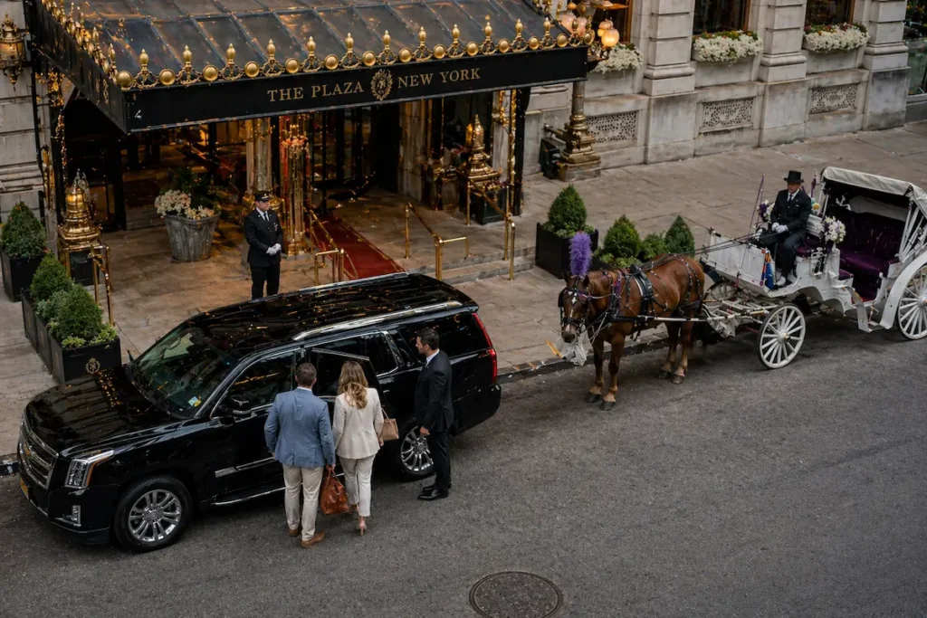 JFK car service to Manhattan with chauffeur dropping passengers outside Plaza Hotel next to black SUV