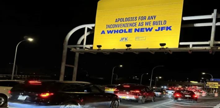 JFK Airport traffic during terminal construction with pickup congestion and signage for airport arrivals.
