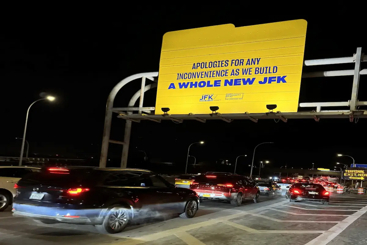 JFK Airport traffic during terminal construction with pickup congestion and signage for airport arrivals.
